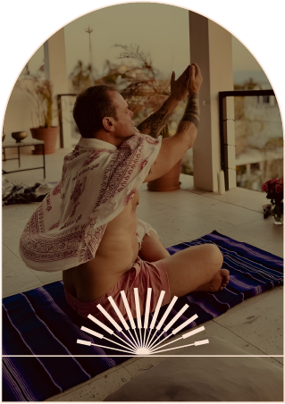 Dale in a seated stretch on a mat, on a covered terrace